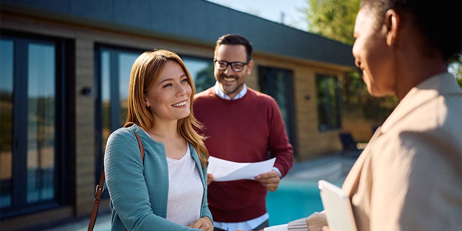 Homebuyers meeting with a Kansas City real estate agent outside a home during a property tour