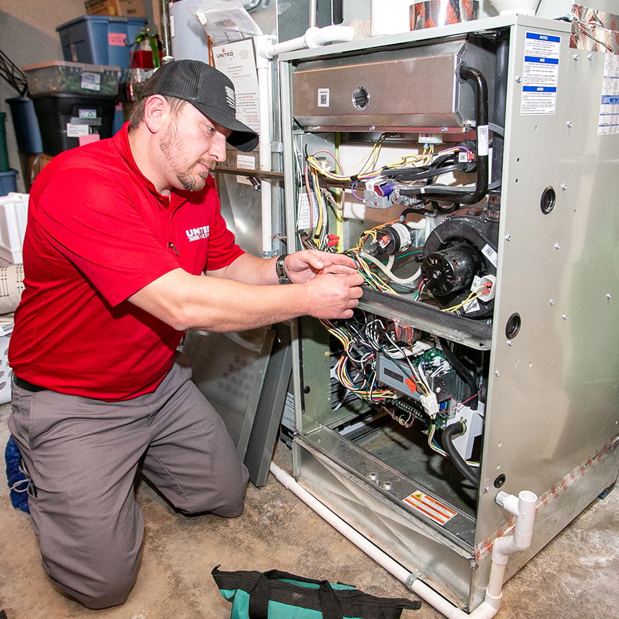 United Heating technician working on the inside of a furnace to restore heat back to a client's home in Kansas City United Heating technician working on the inside of a furnace to restore heat back to a client's home in Kansas City